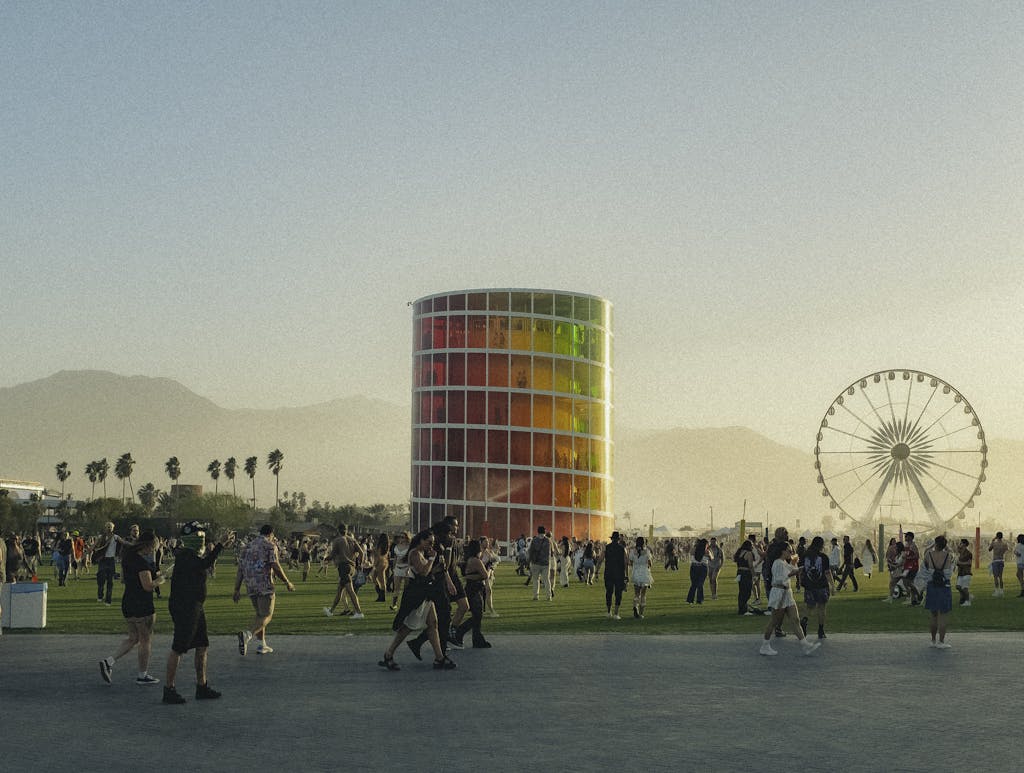 People enjoying a lively music festival with a colorful tower and Ferris wheel backdrop.