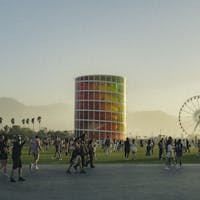 People enjoying a lively music festival with a colorful tower and Ferris wheel backdrop.